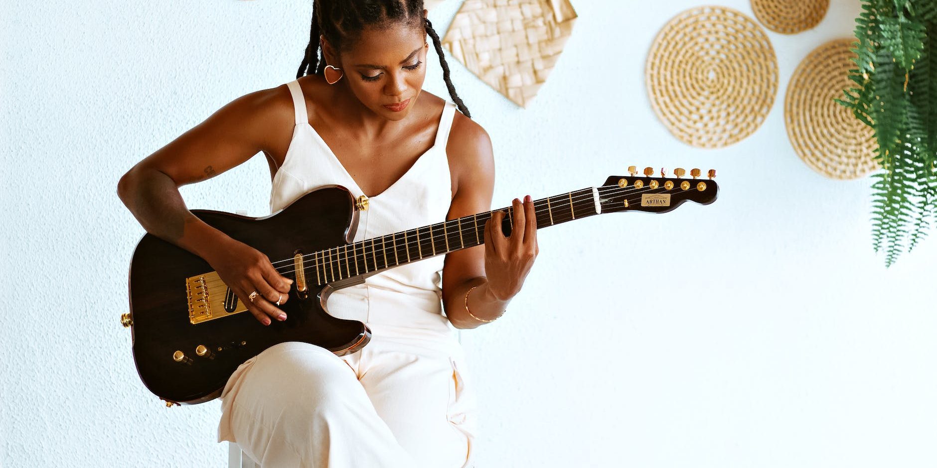 photo of a young woman sitting and playing an electric guitar