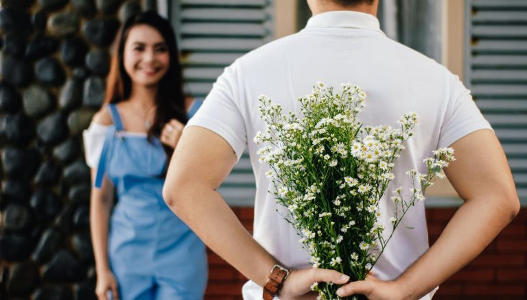 man holding baby s breath flower in front of woman standing near marble wall