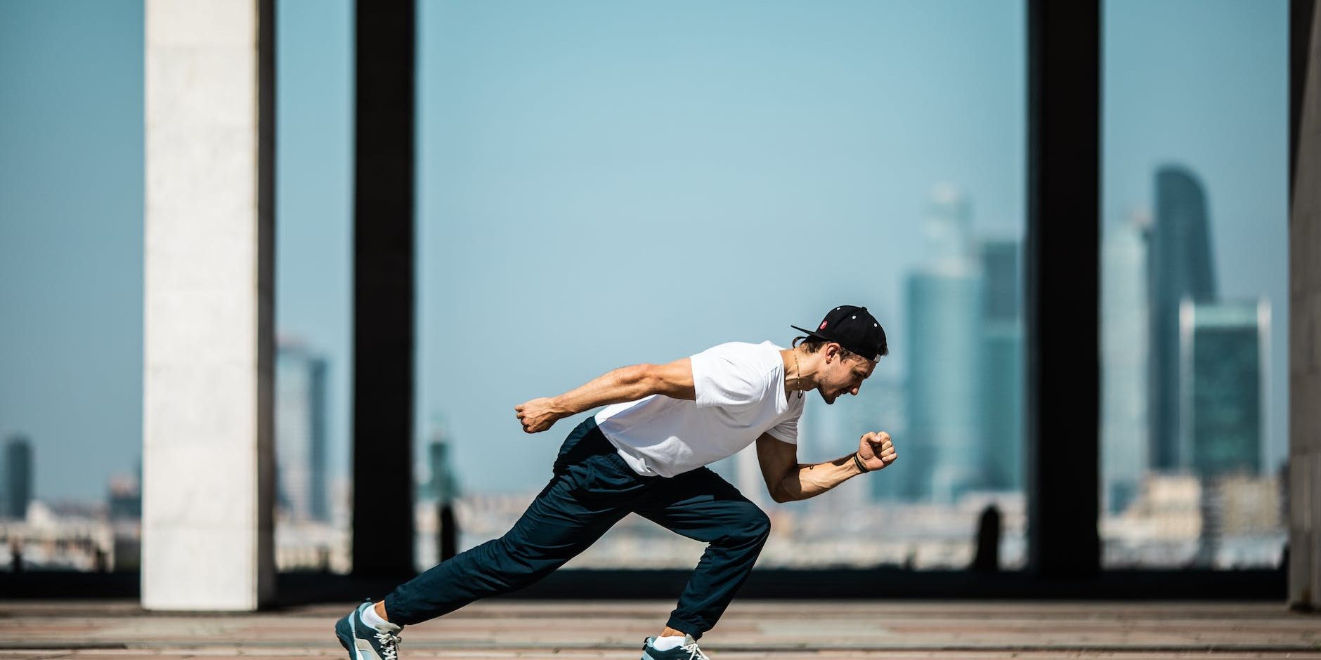 man in white t shirt and black pants in a running position