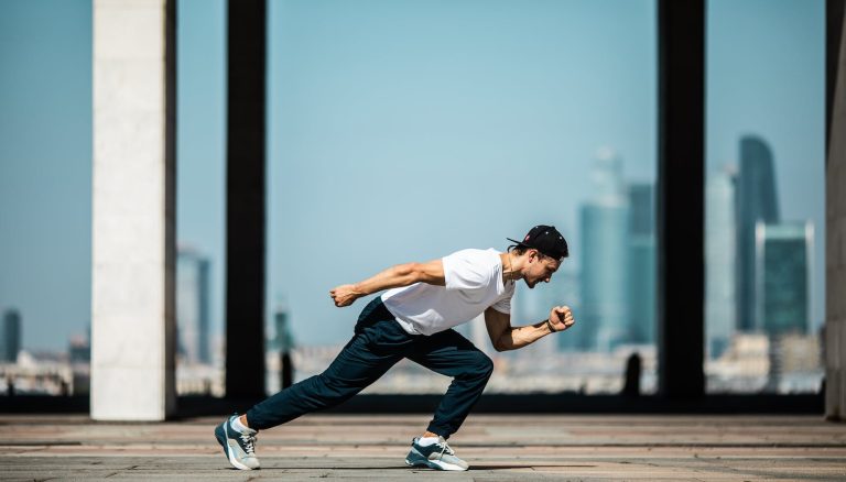 man in white t shirt and black pants in a running position