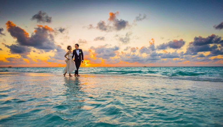 man and woman walking of body of water