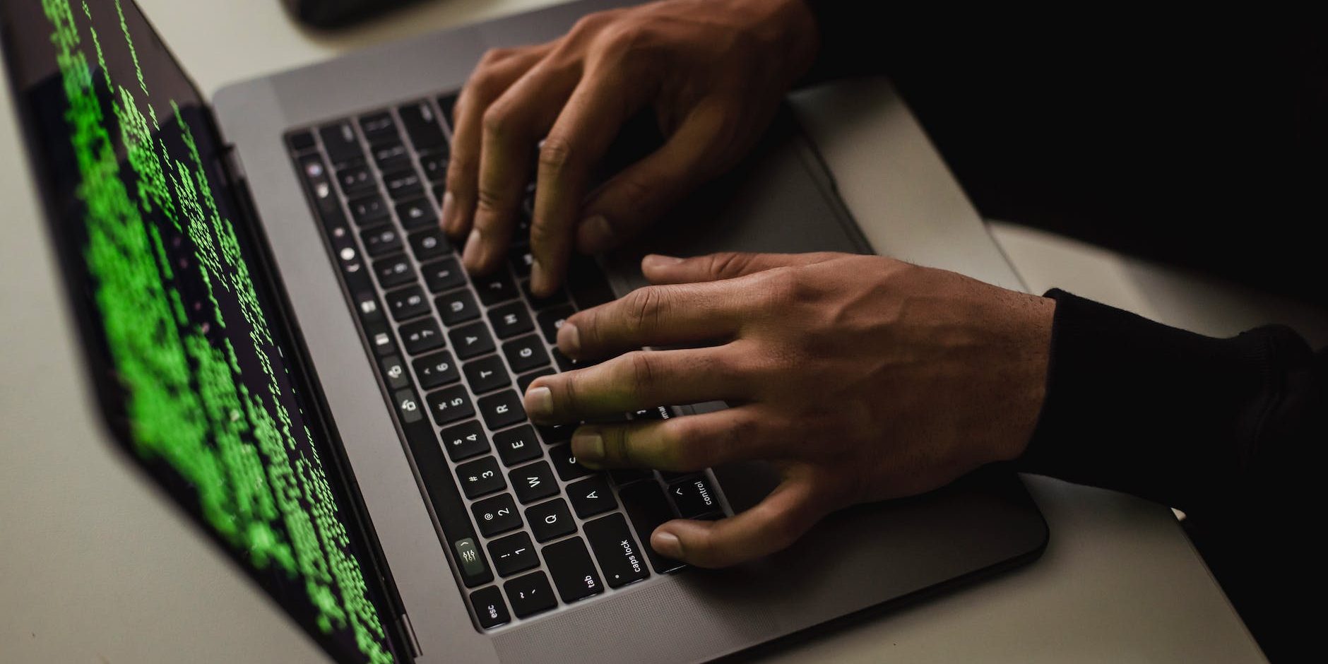 crop cyber spy hacking system while typing on laptop