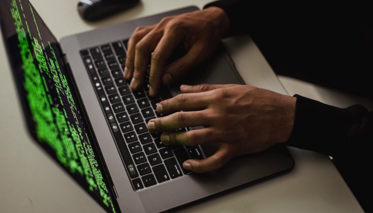crop cyber spy hacking system while typing on laptop