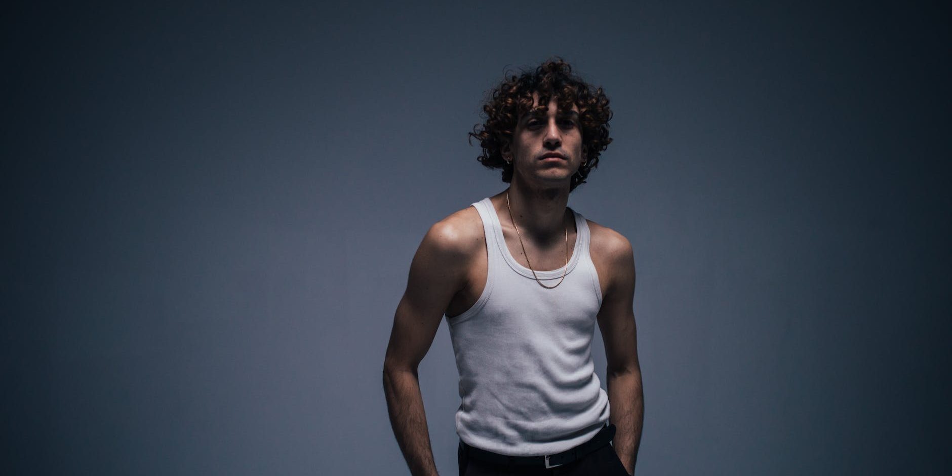 man in white tank top with curly hair