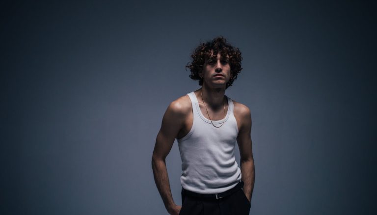 man in white tank top with curly hair
