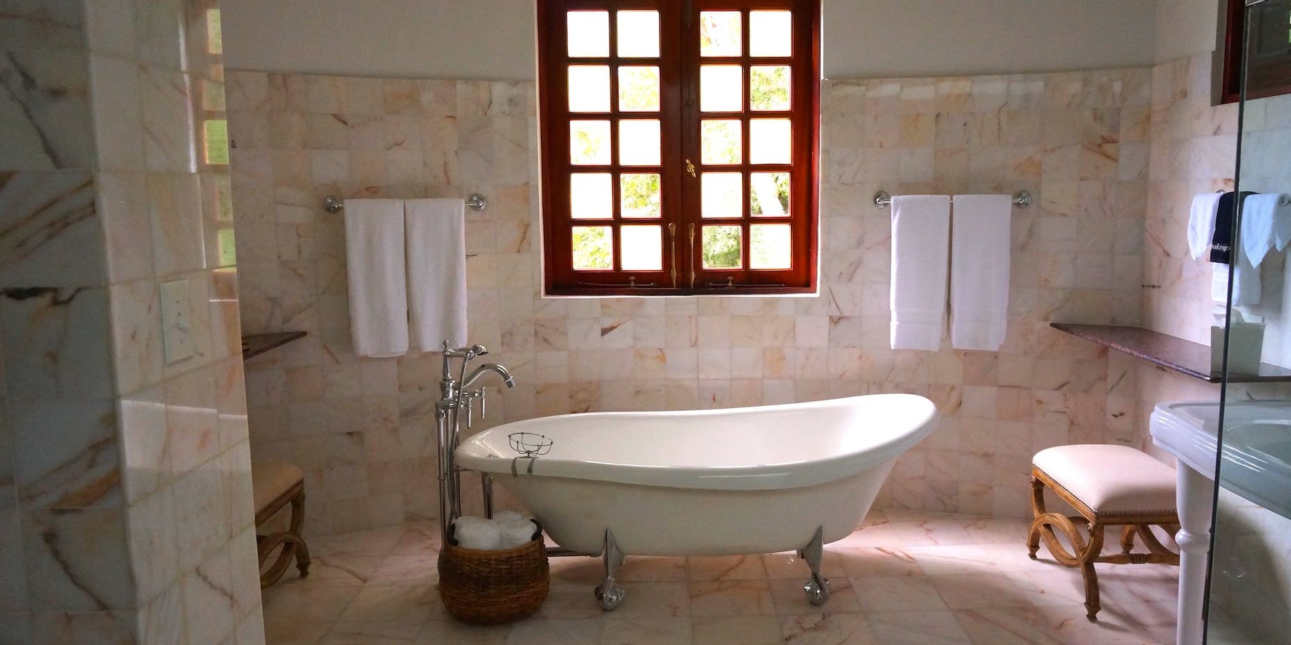 white bathtub on white tile bathroom near brown framed clear glass window