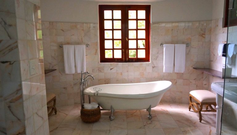 white bathtub on white tile bathroom near brown framed clear glass window