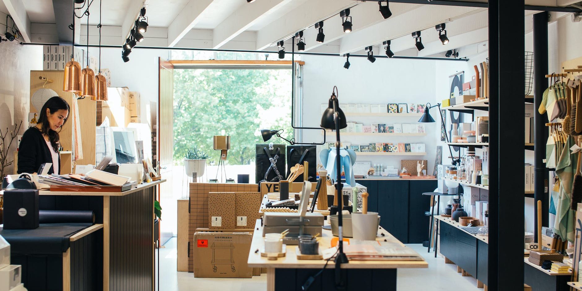 young ethnic female employee standing at counter in creative gift shop