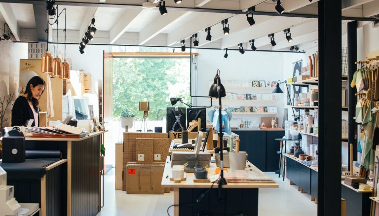 young ethnic female employee standing at counter in creative gift shop