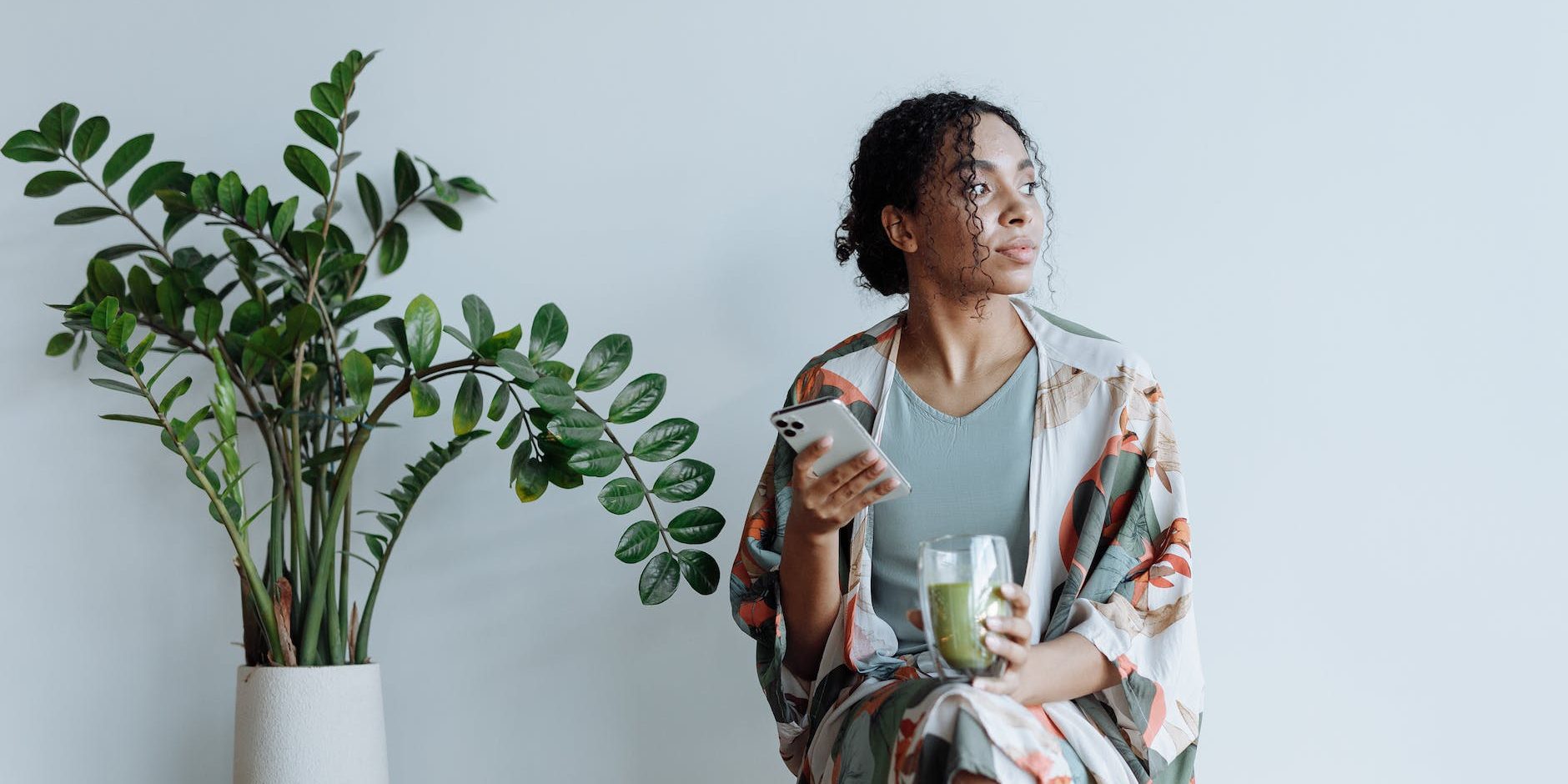 photo of woman sitting beside an indoor plant