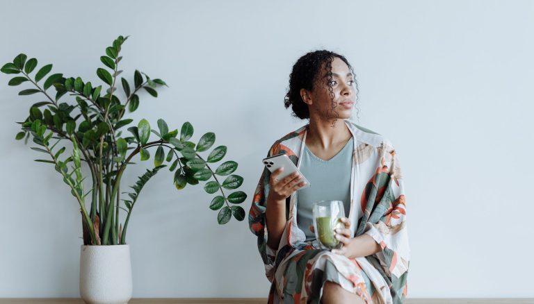 photo of woman sitting beside an indoor plant