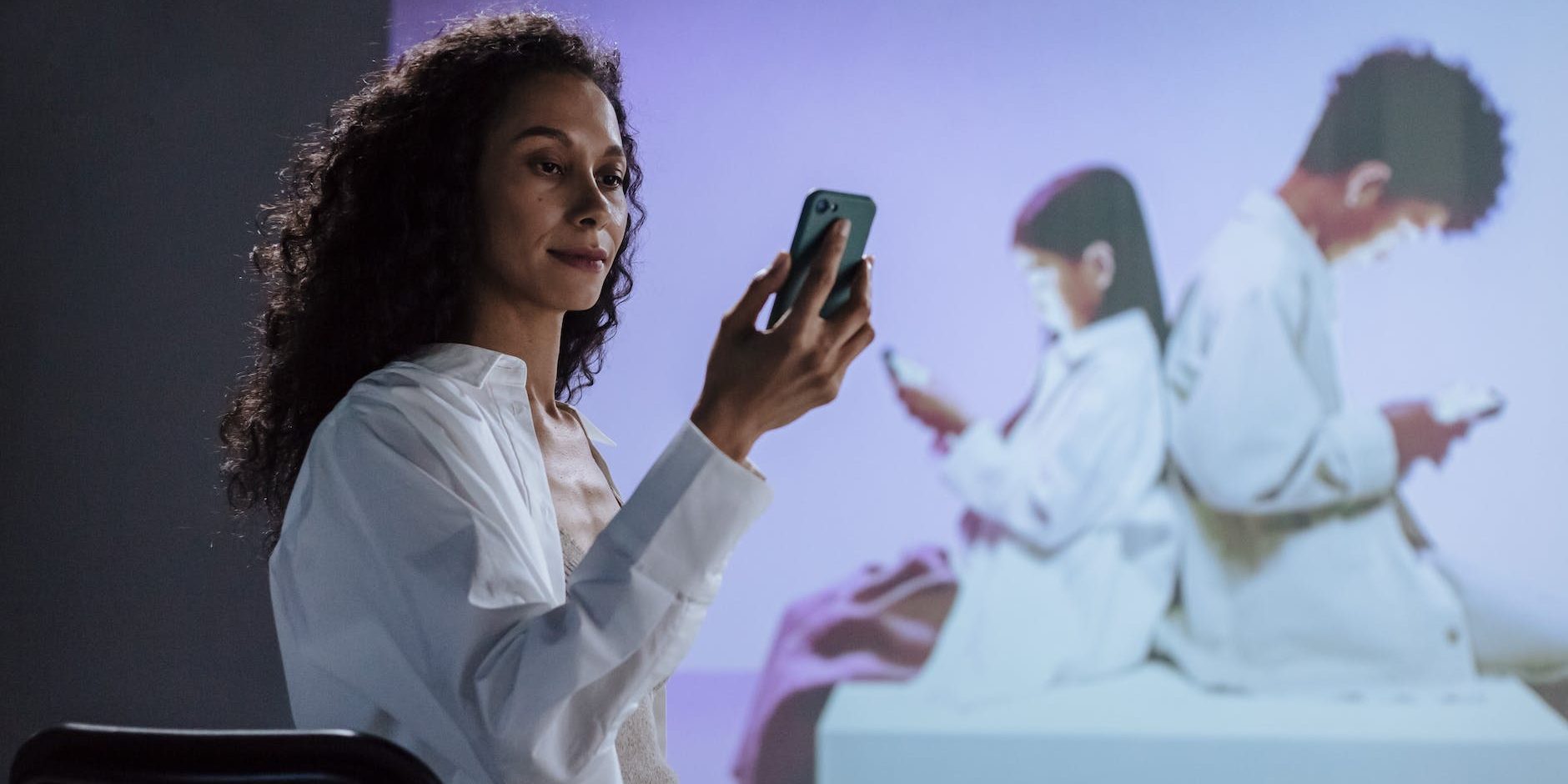 sitting woman in lab coat looking at smartphone