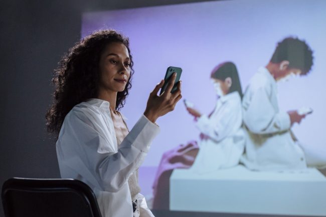 sitting woman in lab coat looking at smartphone