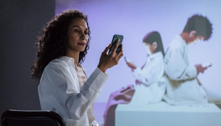 sitting woman in lab coat looking at smartphone