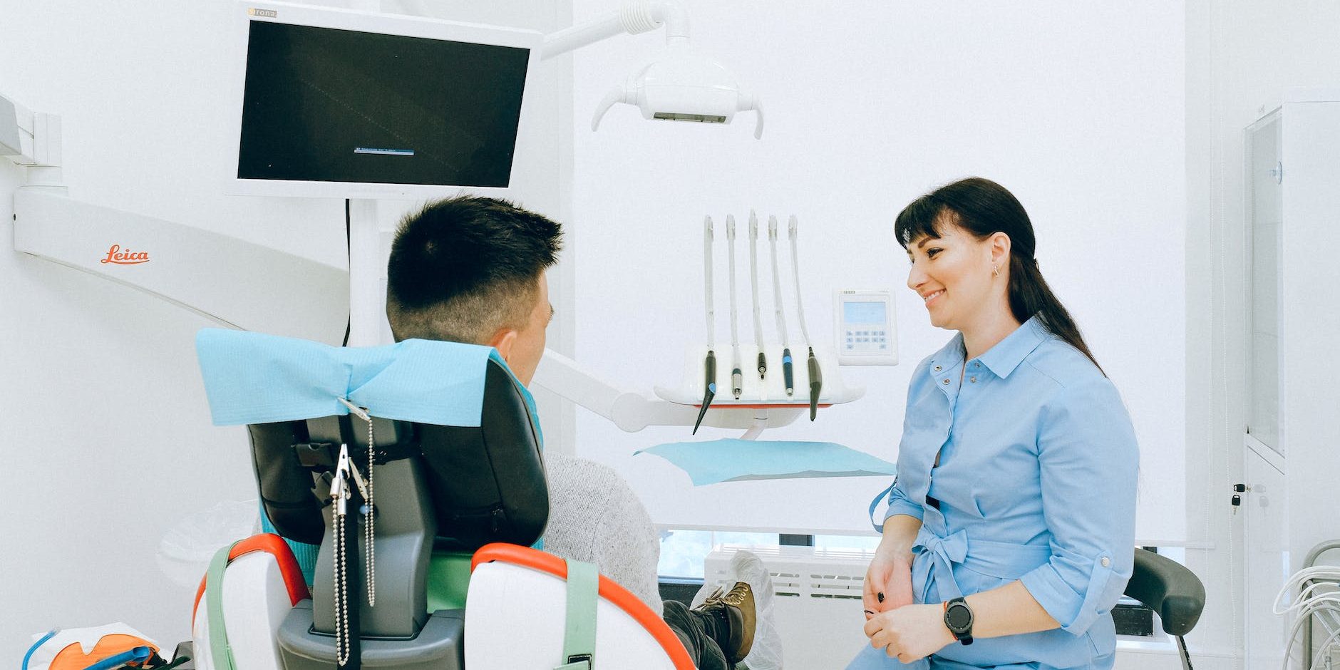 cheerful stomatologist talking with patient sitting in dental chair