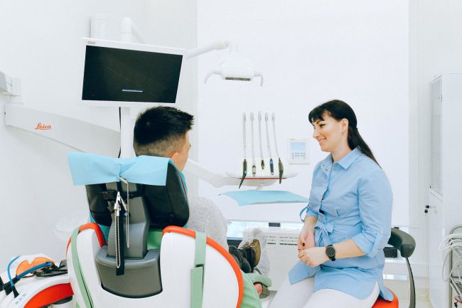 cheerful stomatologist talking with patient sitting in dental chair