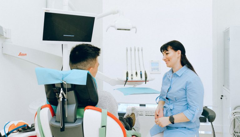 cheerful stomatologist talking with patient sitting in dental chair