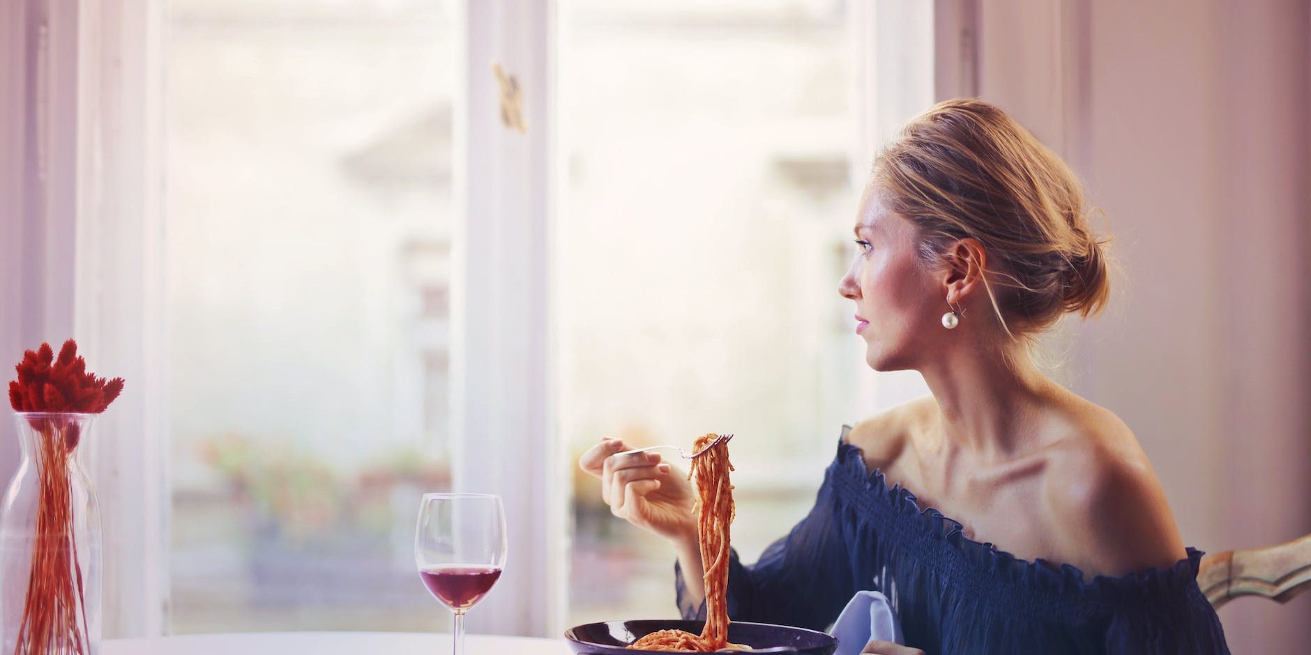 woman sitting on chair while eating pasta dish