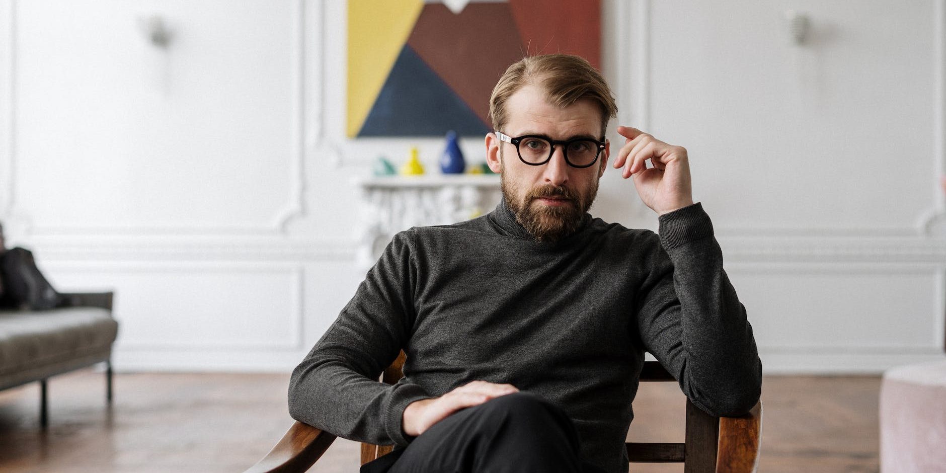 man in black sweater sitting on brown wooden chair
