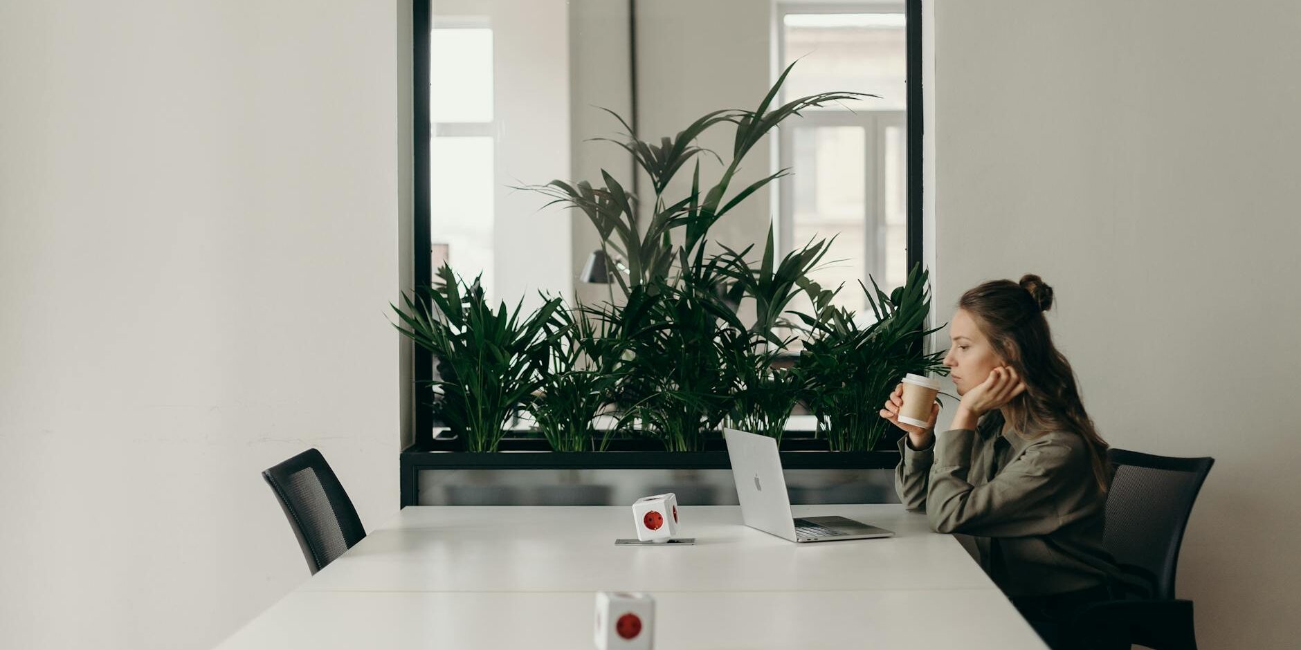 woman in black and gray jacket sitting on chair in front of silver macbook