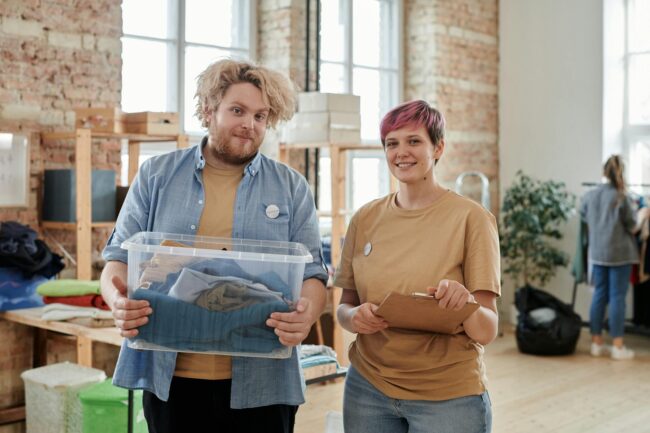 man and woman volunteers with box of clothes