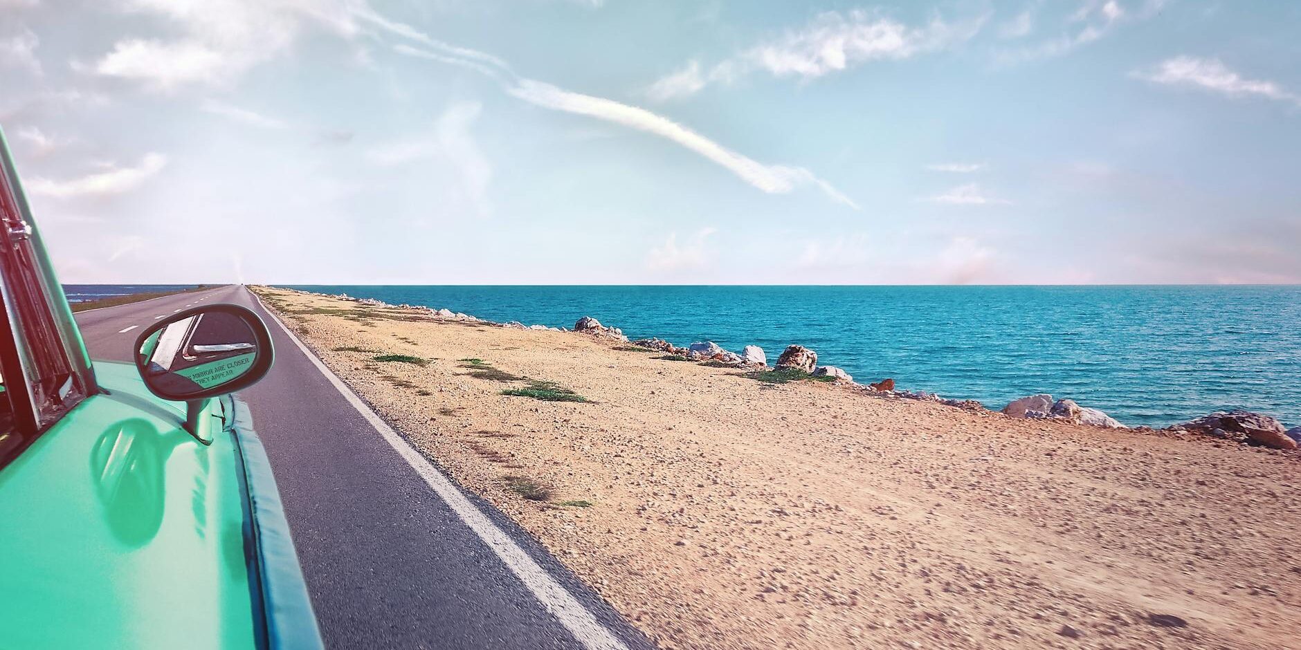 green car near seashore with blue ocean