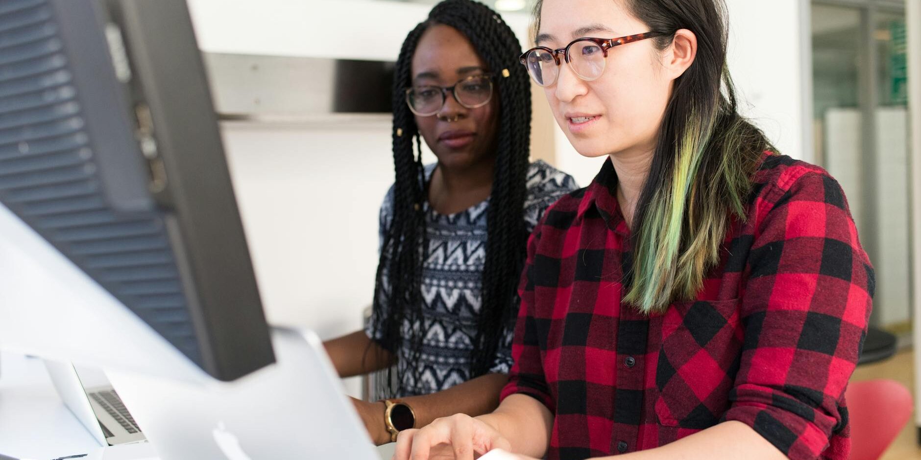 woman wearing red and black checkered blouse using macbook
