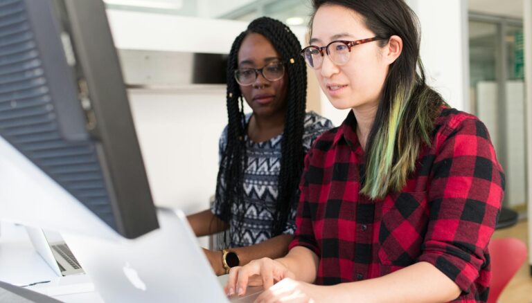 woman wearing red and black checkered blouse using macbook