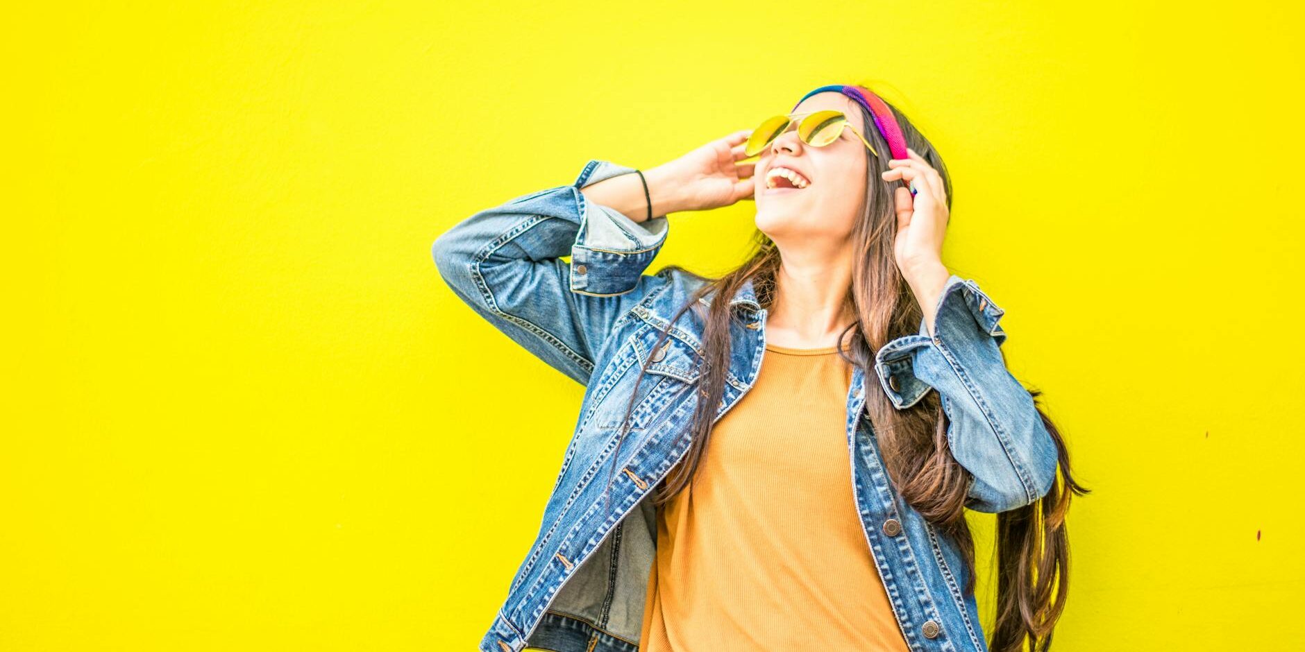 smiling woman looking upright standing against yellow wall