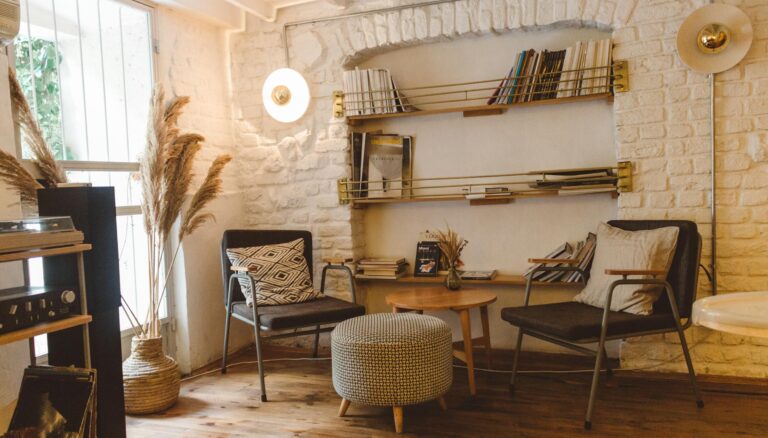 round brown wooden table between two chairs and ottoman chair