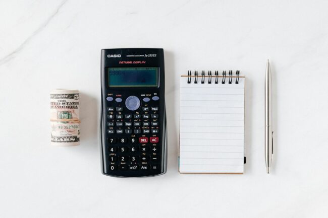 composition of calculator with paper money and notebook with pen