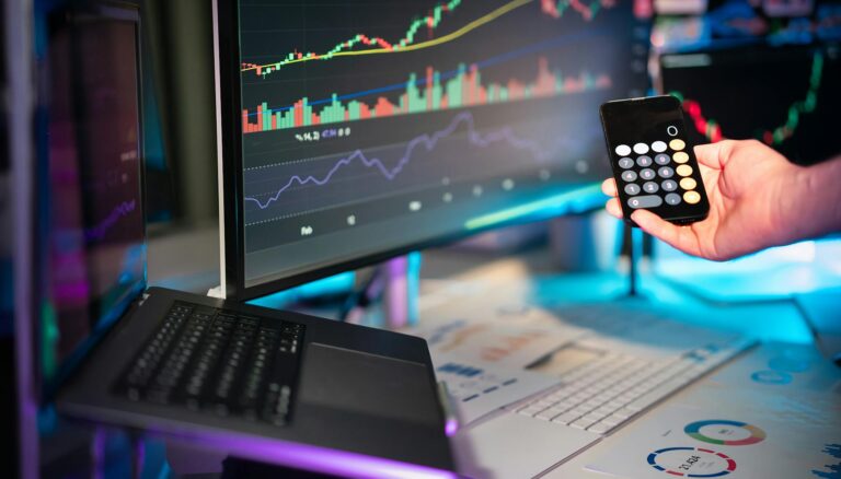 business economy hand holding smartphone calculator financial charts