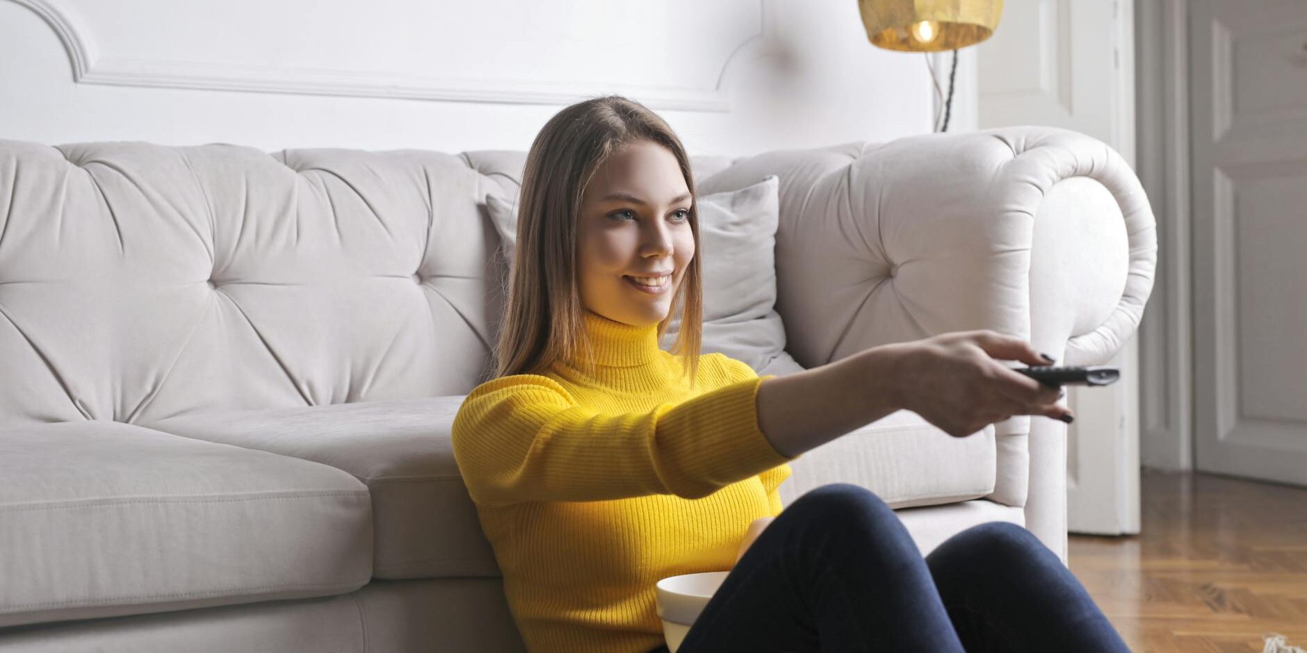 happy young relaxed woman watching tv at home