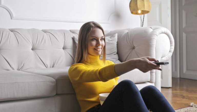 happy young relaxed woman watching tv at home