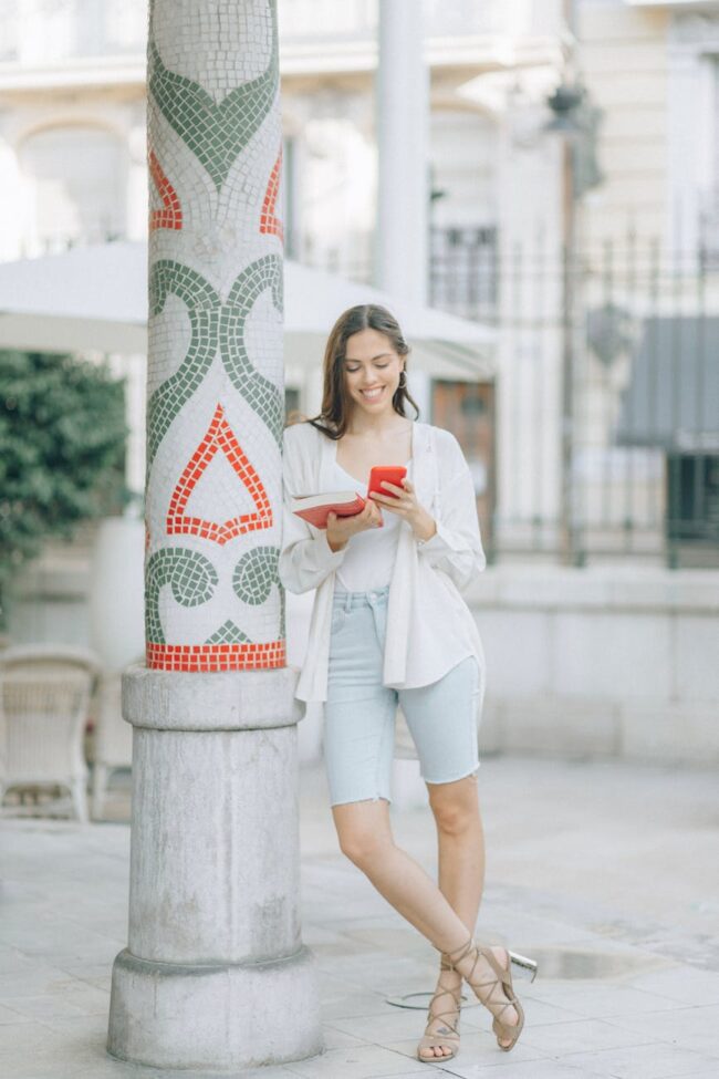 woman in white long sleeve shirt and white pants sitting on white and red floral concrete