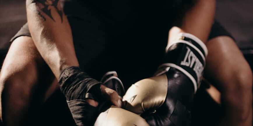 man in black tank top wearing blue and white boxing gloves