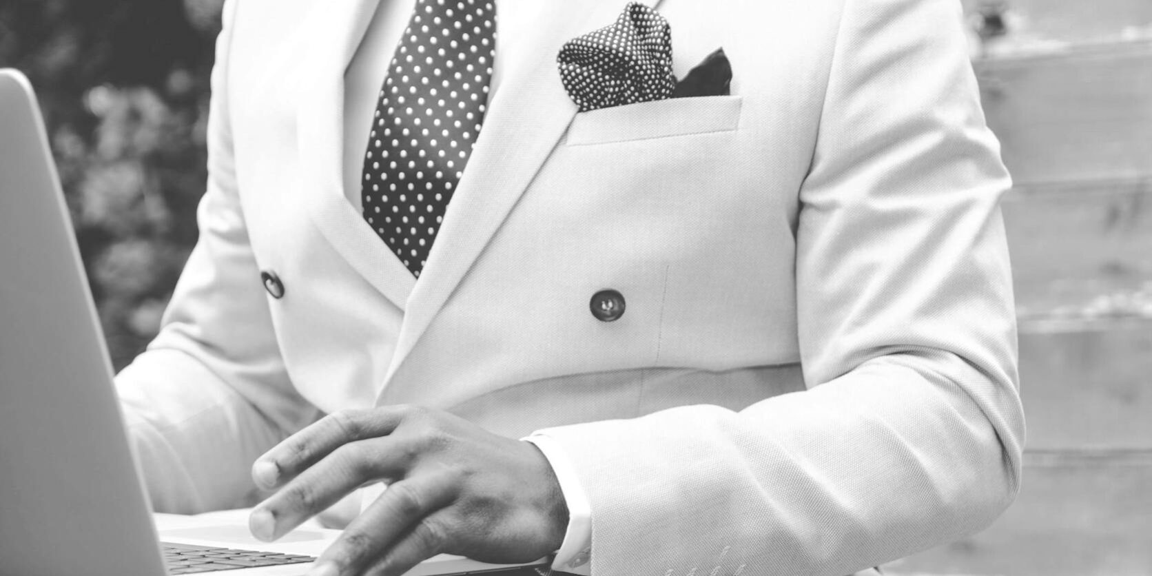 grayscale photo of man wearing white suit jacket