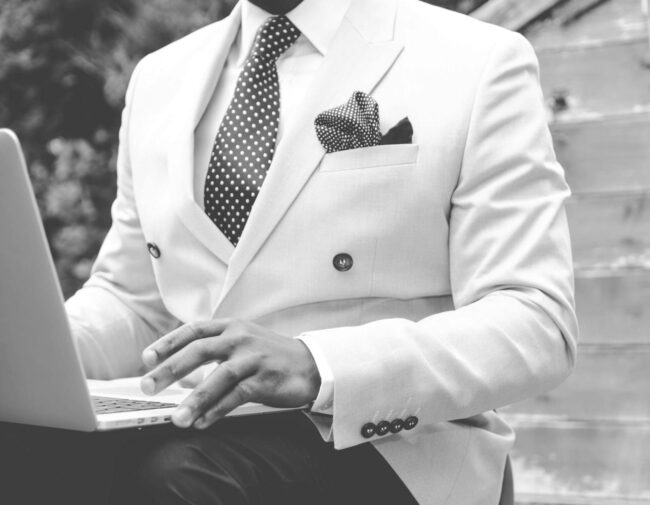 grayscale photo of man wearing white suit jacket