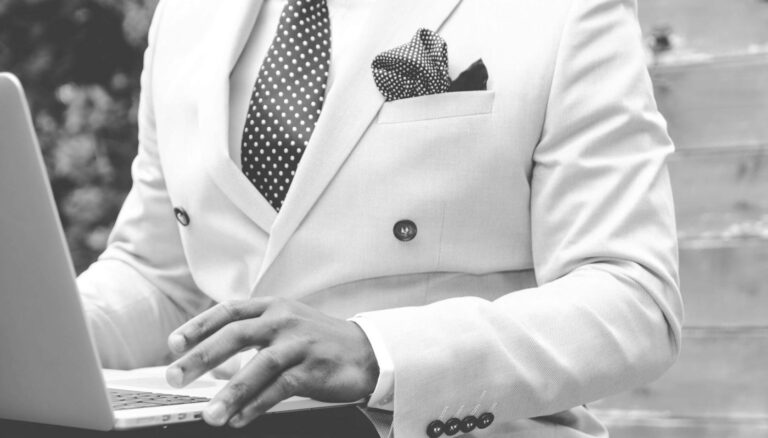grayscale photo of man wearing white suit jacket