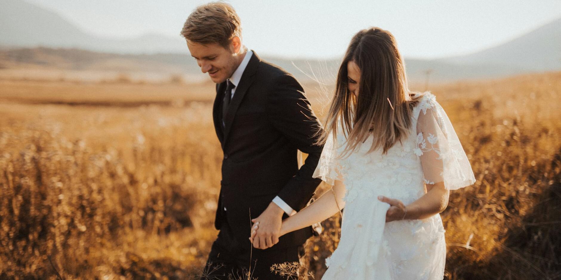 shallow focus photo of man in black formal suit holding woman s hand in white dress