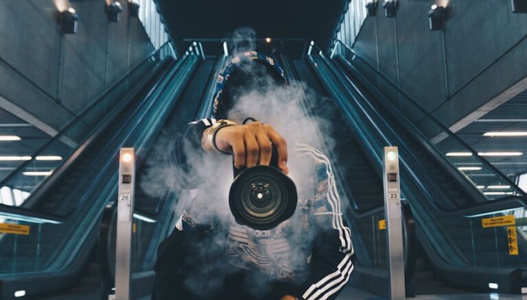 man holding camera while squating with smoke on face inside building