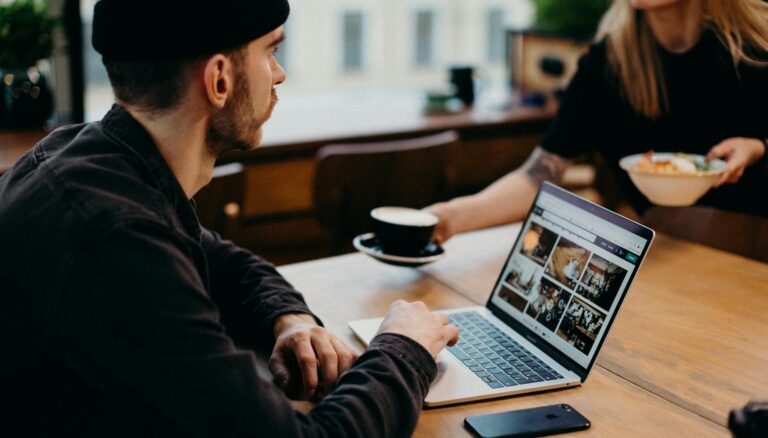 man wearing black jacket using laptop computer sitting beside table