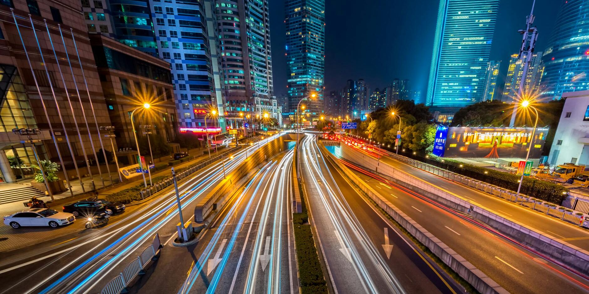 timelapse photography of vehicle on concrete road near in high rise building during nighttime