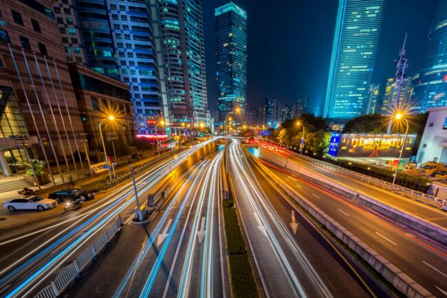 timelapse photography of vehicle on concrete road near in high rise building during nighttime