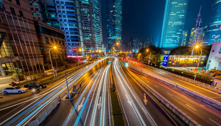 timelapse photography of vehicle on concrete road near in high rise building during nighttime