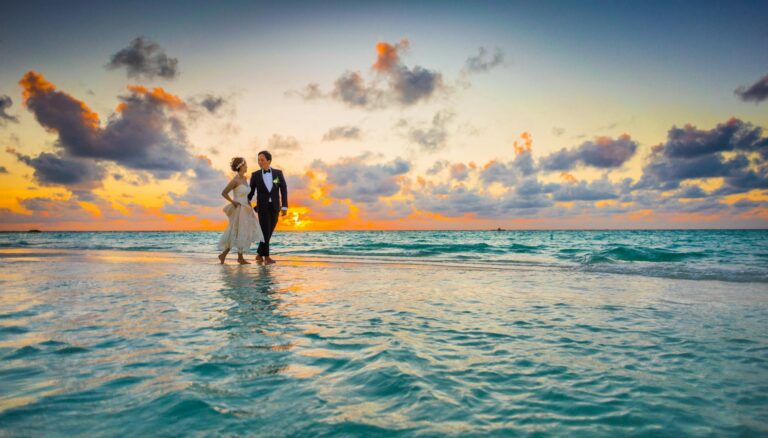 man and woman walking of body of water
