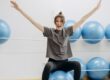woman sitting on a yoga ball with arms raised