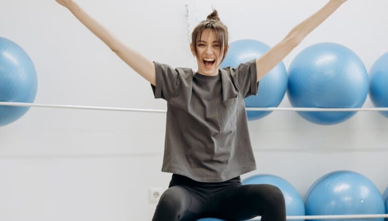 woman sitting on a yoga ball with arms raised