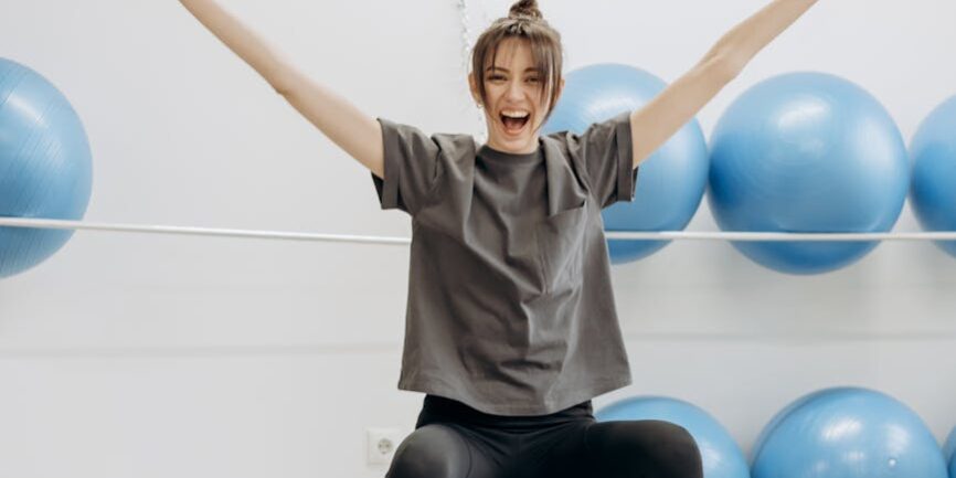 woman sitting on a yoga ball with arms raised