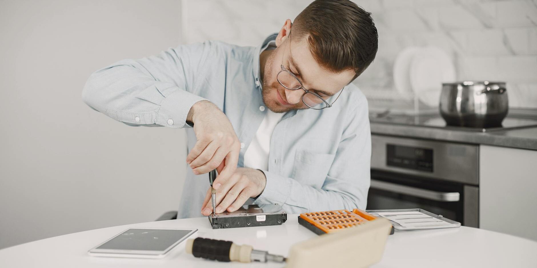 man sitting at a table and tinkering using a screwdriver